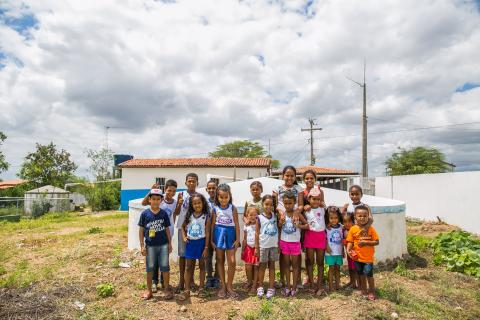 Um grupo de crianças em frente de uma cisterna de água no interior do Brasil